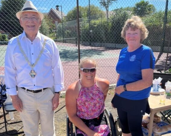Three people in front of a tennis court.