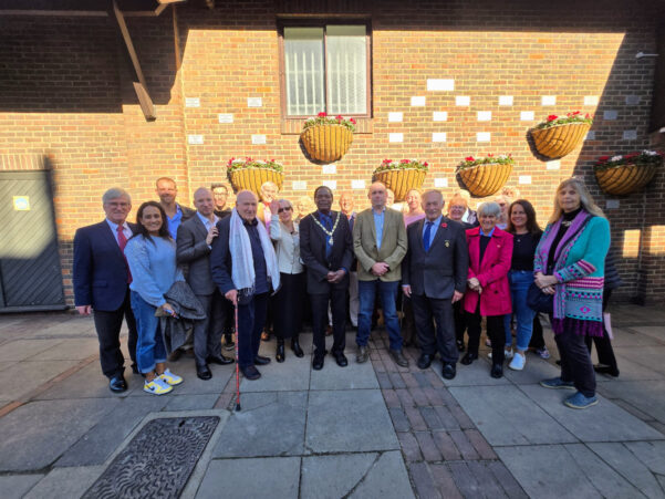 Group of people gathered in front of wall mounted with plaques.