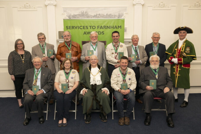 Group of people holding an award. The front row are seated and the back row is standing.