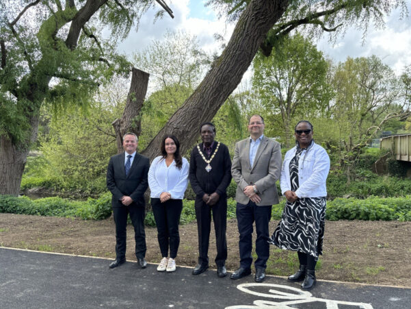 Five people standing on a footpath with trees in the background.