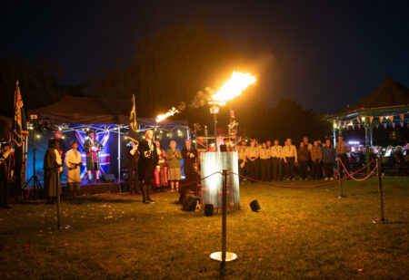 Lighting of a beacon with people in the background.