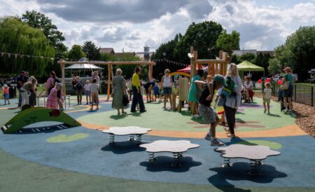 Child jumps between springy platforms in busy playground.