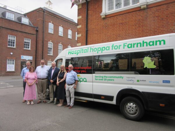 Group of people standing by the side of a hoppa bus.