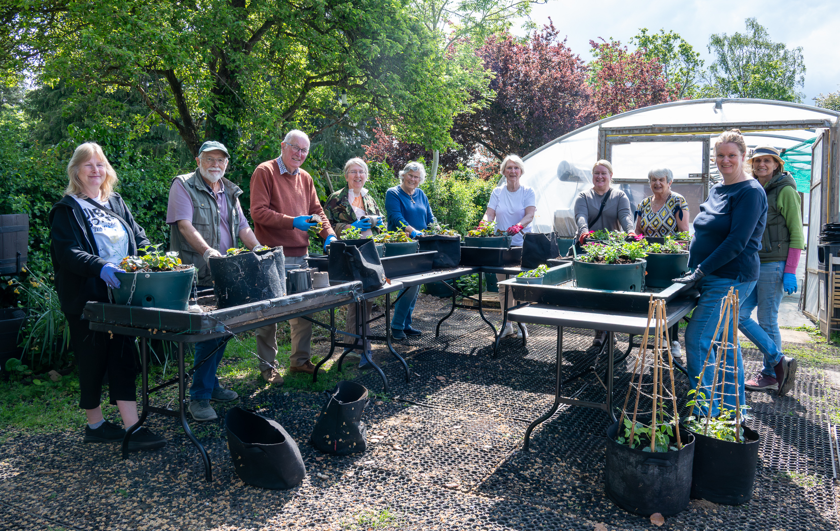Group of people standing at tables planting hanging baskets For Farnham In Bloom